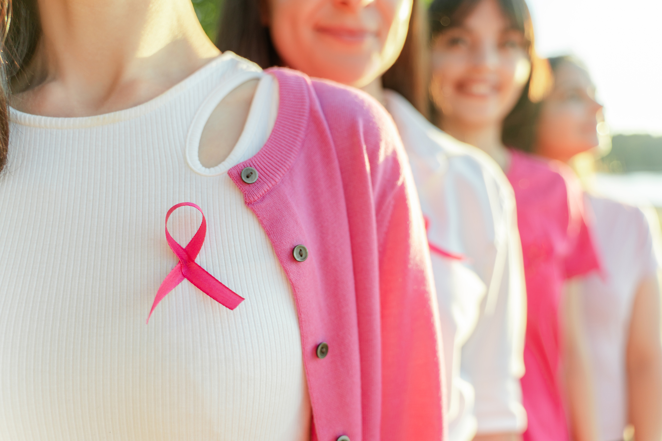 Cropped view of happy smiling women with breast cancer awareness pink ribbon on t-shirts 